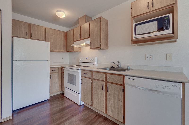 A kitchen with white appliances and wooden cabinets.